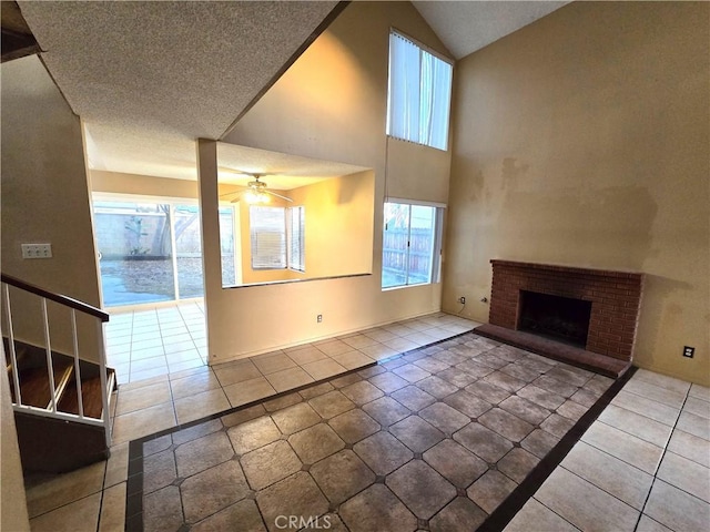 unfurnished living room featuring high vaulted ceiling, a fireplace, tile patterned flooring, ceiling fan, and a textured ceiling