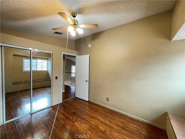 unfurnished bedroom featuring ceiling fan, vaulted ceiling, dark hardwood / wood-style floors, and a textured ceiling