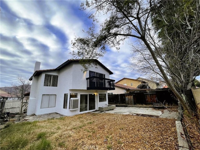 back of house featuring a balcony, a yard, and a patio area