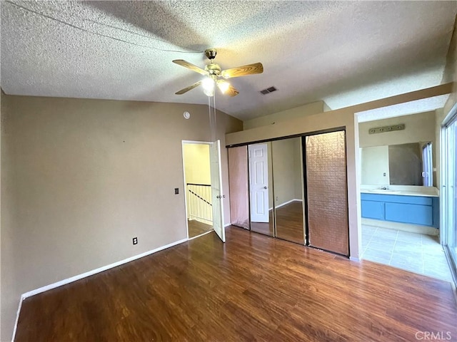 unfurnished bedroom with ceiling fan, hardwood / wood-style floors, a textured ceiling, and ensuite bath