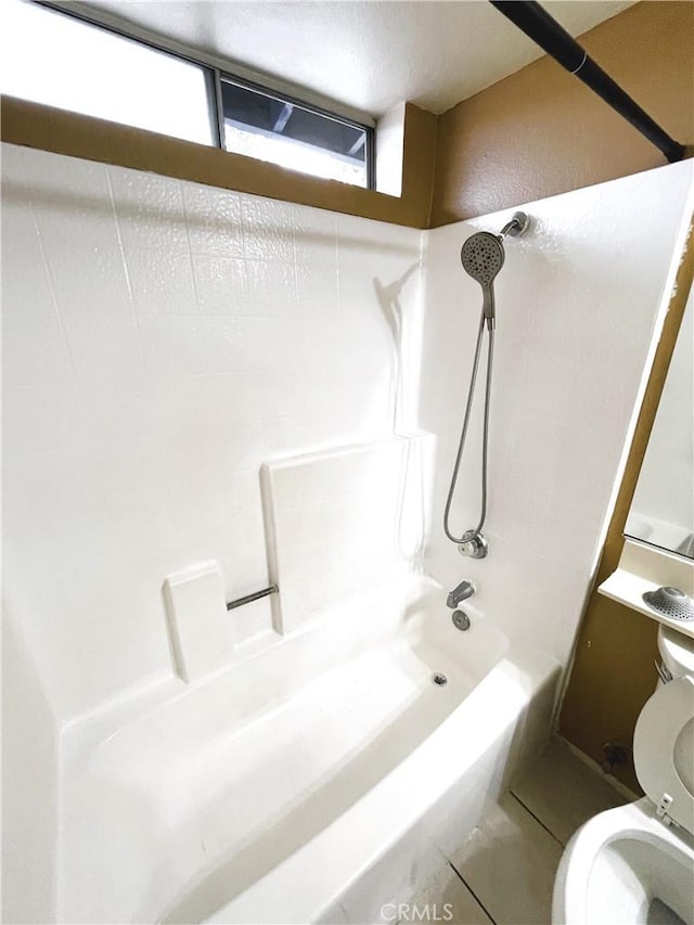 bathroom featuring tile patterned flooring, washtub / shower combination, and toilet