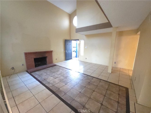 unfurnished living room featuring light tile patterned flooring, high vaulted ceiling, and a brick fireplace