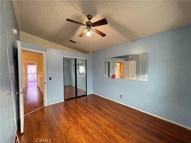 unfurnished bedroom featuring hardwood / wood-style floors, vaulted ceiling, a closet, and a textured ceiling