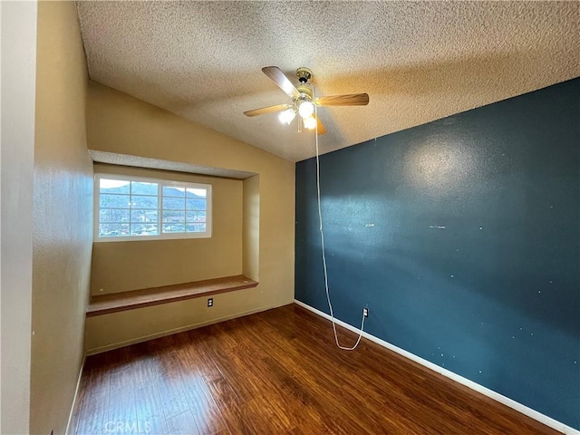 empty room with wood-type flooring, lofted ceiling, ceiling fan, and a textured ceiling