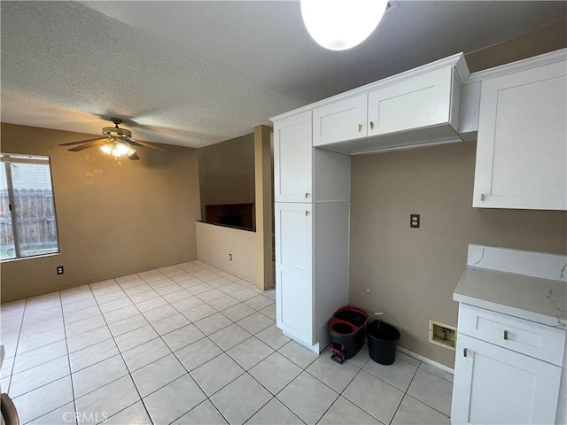 kitchen featuring ceiling fan, light tile patterned floors, a textured ceiling, and white cabinets