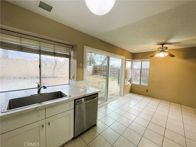 kitchen featuring sink, a textured ceiling, light tile patterned floors, stainless steel dishwasher, and ceiling fan