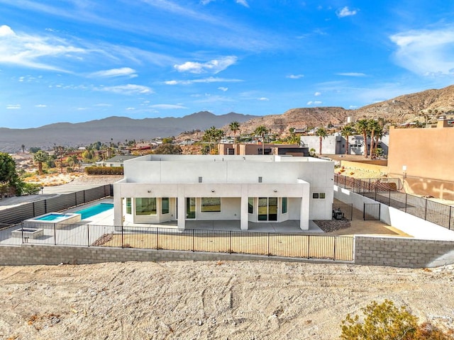 rear view of property featuring a fenced in pool, a mountain view, and a patio