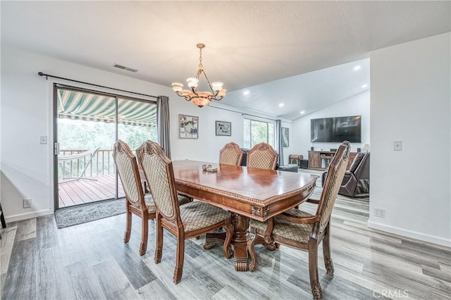 dining room with light hardwood / wood-style flooring, a chandelier, and vaulted ceiling