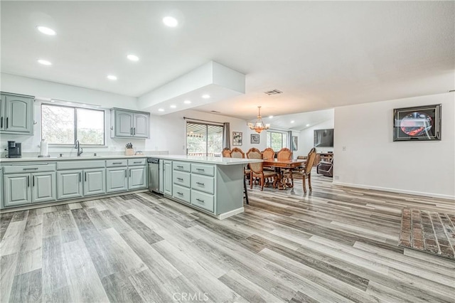 kitchen featuring sink, an inviting chandelier, decorative light fixtures, kitchen peninsula, and light wood-type flooring