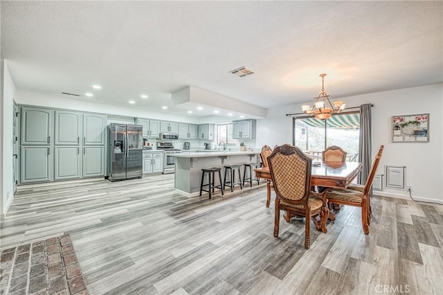 dining space featuring sink, a textured ceiling, light hardwood / wood-style flooring, and a chandelier