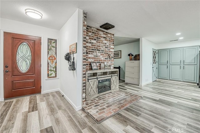 entrance foyer with a fireplace and light hardwood / wood-style floors