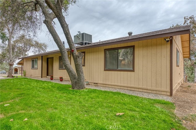 back of property featuring cooling unit and a lawn