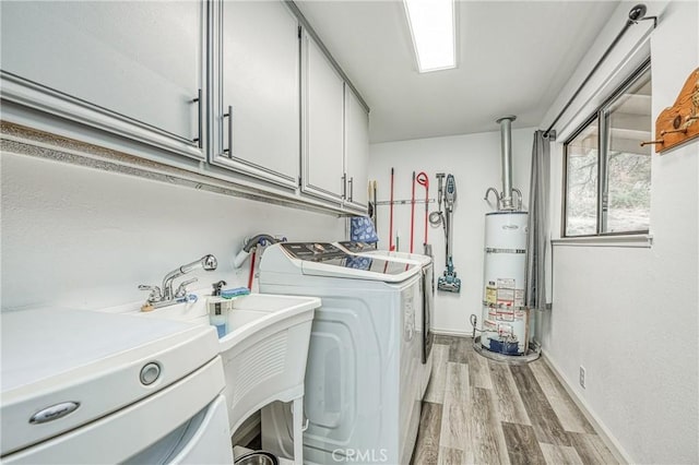 clothes washing area with separate washer and dryer, cabinets, light hardwood / wood-style floors, and water heater