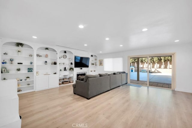 living room with built in shelves and light hardwood / wood-style flooring