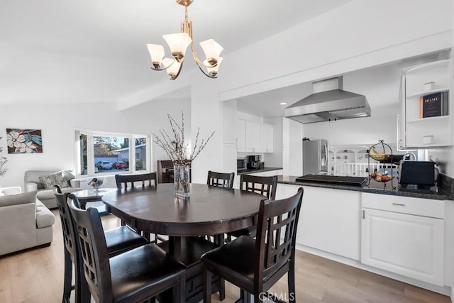 dining room featuring lofted ceiling with beams, a chandelier, and light wood-type flooring