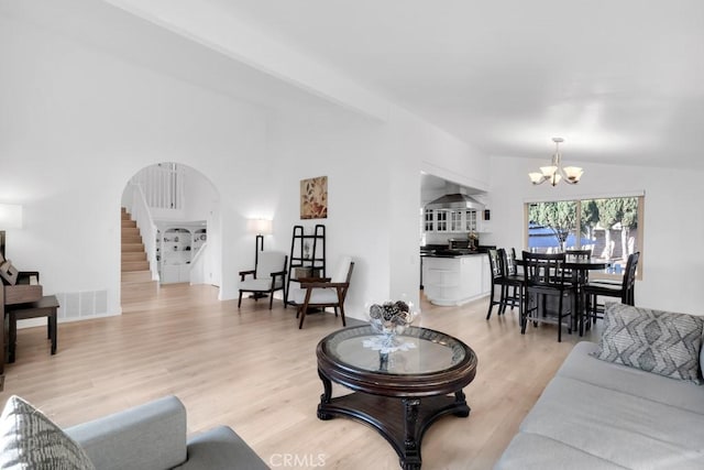 living room featuring light hardwood / wood-style floors, a chandelier, and vaulted ceiling