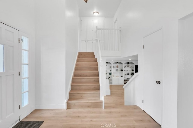 staircase with hardwood / wood-style flooring and a towering ceiling