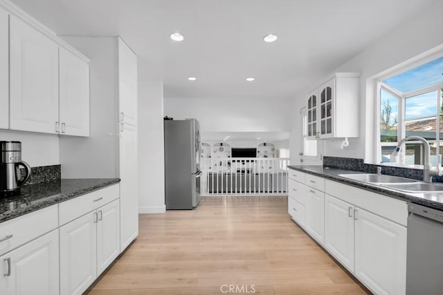 kitchen with dishwashing machine, sink, stainless steel refrigerator, white cabinetry, and light wood-type flooring