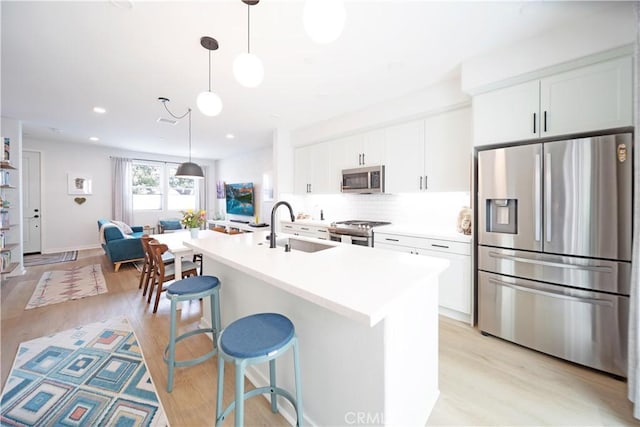 kitchen featuring appliances with stainless steel finishes, a breakfast bar, pendant lighting, white cabinetry, and sink