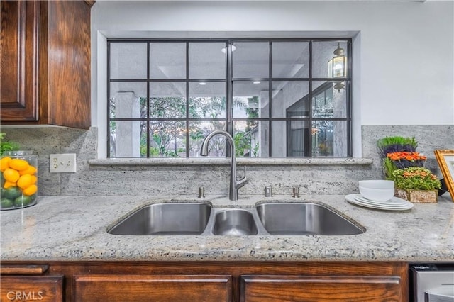 interior details with tasteful backsplash, light stone countertops, and sink