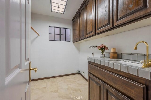 clothes washing area with cabinet space and baseboards