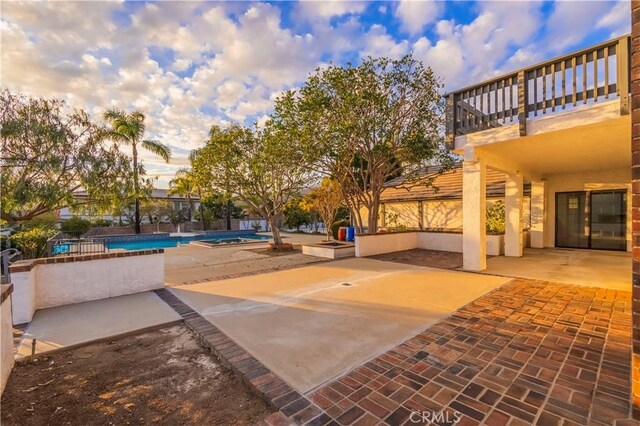 view of patio with an outdoor pool and a balcony