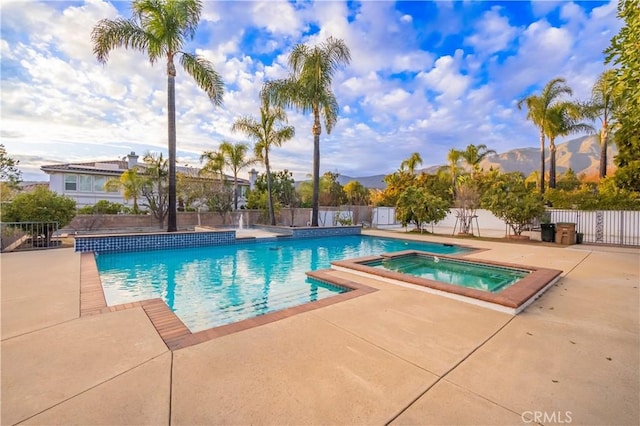 view of swimming pool with a mountain view, a patio area, and an in ground hot tub