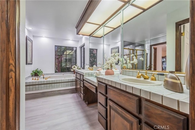 bathroom with vanity and tiled bath