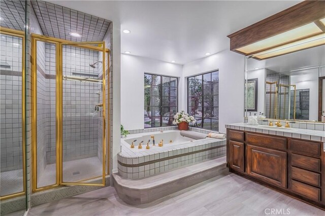 full bathroom featuring recessed lighting, a shower stall, vanity, and a tub with jets