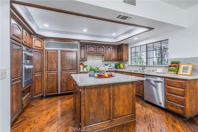 kitchen with sink, a center island, appliances with stainless steel finishes, dark hardwood / wood-style flooring, and a tray ceiling