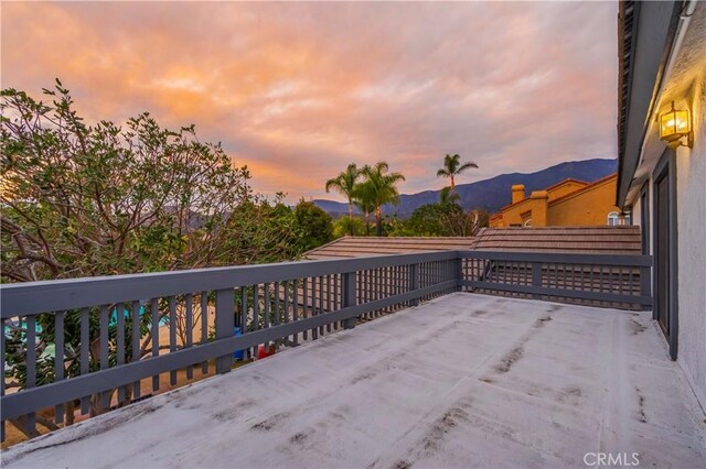 patio terrace at dusk featuring a balcony and a mountain view