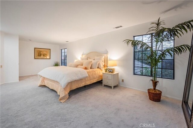 bedroom featuring light carpet, visible vents, and baseboards