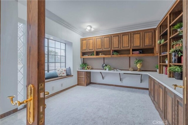 unfurnished office featuring light carpet, crown molding, and built in desk