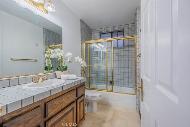 bathroom featuring bath / shower combo with glass door, vanity, toilet, and tile patterned floors