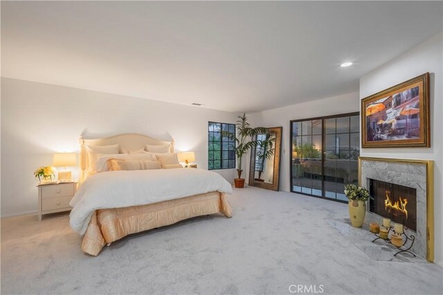 bedroom featuring access to outside, a premium fireplace, and carpet flooring