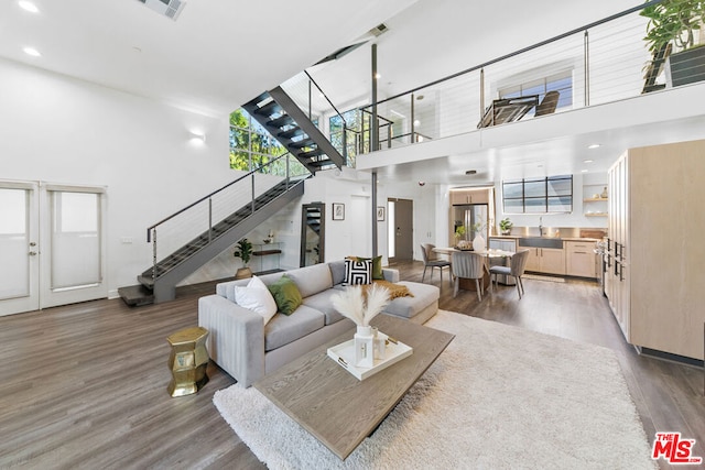 living room featuring a towering ceiling, wood-type flooring, and sink