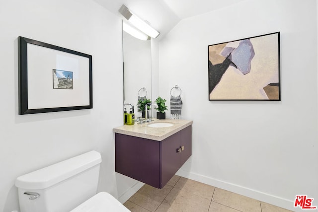 bathroom featuring vanity, tile patterned flooring, lofted ceiling, and toilet