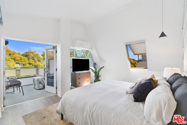 bedroom featuring multiple windows, lofted ceiling, a wall unit AC, and light hardwood / wood-style flooring