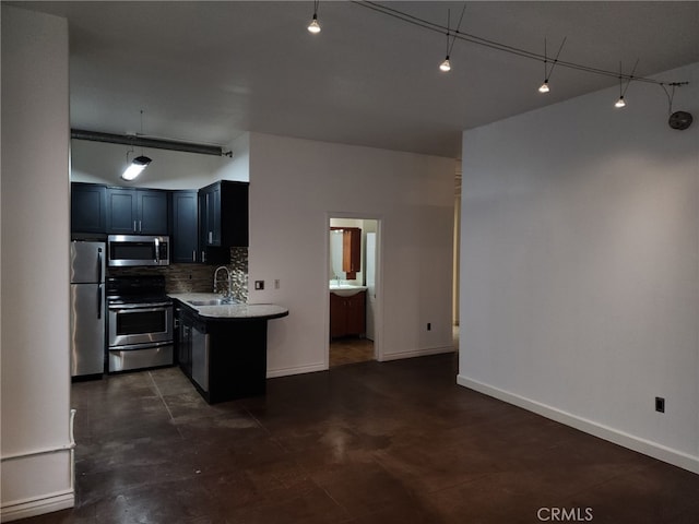 kitchen featuring stainless steel appliances, kitchen peninsula, sink, and decorative backsplash