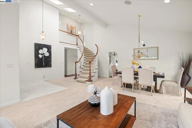 carpeted living room with beam ceiling, high vaulted ceiling, and a skylight