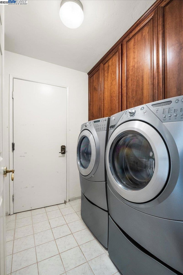 washroom with cabinets, light tile patterned floors, and washing machine and clothes dryer