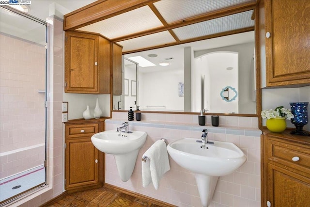 bathroom featuring parquet flooring, an enclosed shower, tile walls, and double sink