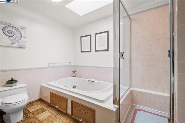 bathroom featuring tile walls, a skylight, plus walk in shower, and toilet