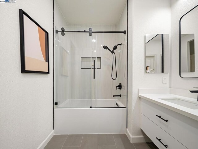 bathroom with tile patterned flooring, vanity, and bath / shower combo with glass door