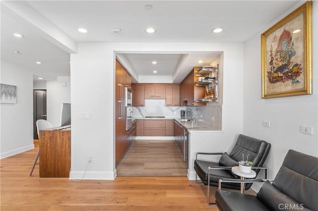 kitchen featuring appliances with stainless steel finishes, sink, decorative backsplash, and light hardwood / wood-style flooring