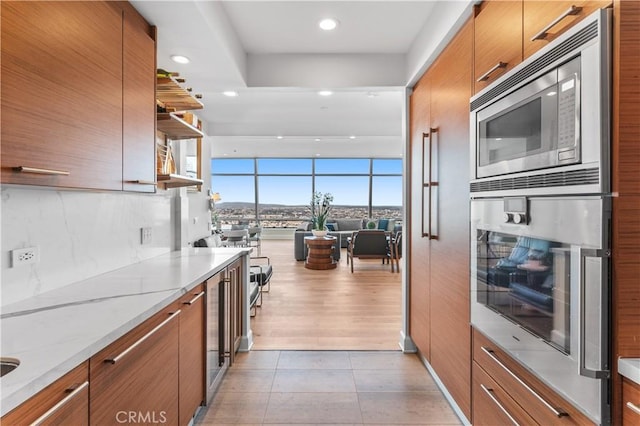 kitchen featuring light tile patterned flooring, light stone counters, stainless steel microwave, expansive windows, and decorative backsplash