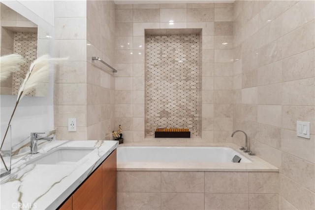 bathroom with vanity, tile walls, and tiled tub