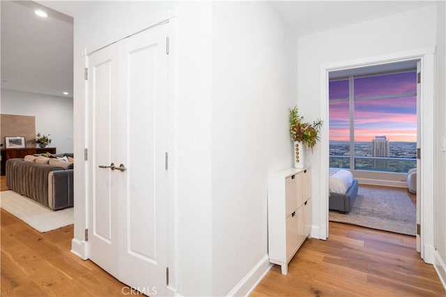 corridor with recessed lighting, light wood finished floors, and baseboards