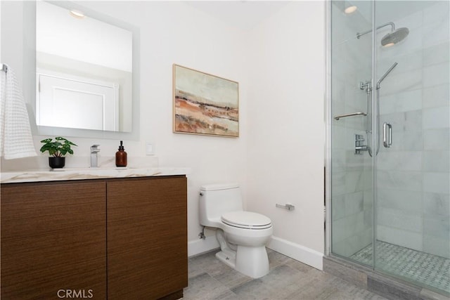 bathroom with vanity, baseboards, a shower stall, and toilet