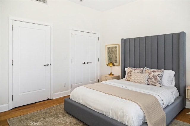 bedroom with baseboards, wood finished floors, and a closet